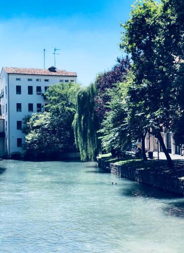 a river with trees and a building in the background at Palazzina300 in Treviso