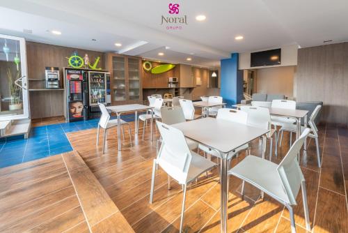 a restaurant with white tables and white chairs at Nuevo Norat Sanxenxo in Sanxenxo