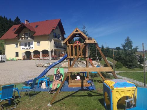 a woman is sitting on a playground swing at Nartorama HotRest in Zieleniec