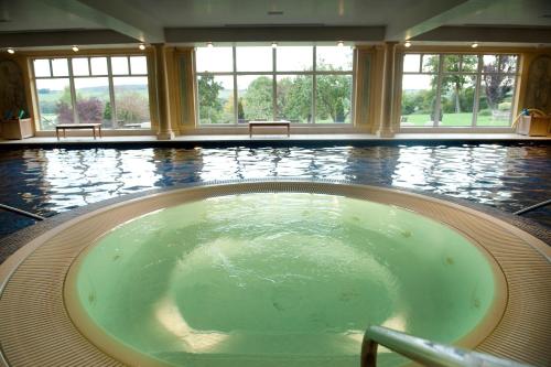 a jacuzzi tub in a large room with windows at Danesfield House Hotel And Spa in Marlow