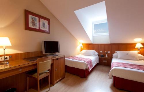 a hotel room with two beds and a desk with a computer at Ateneo Puerta del Sol in Madrid