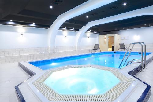 a large pool with a hot tub in a building at Qubus Hotel Wrocław in Wrocław