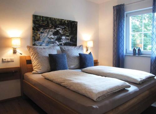 1 dormitorio con 1 cama grande con almohadas azules en Ferienwohnung am Woid, en Waldkirchen