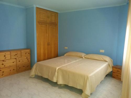 1 dormitorio azul con 1 cama y armario de madera en Apartamento de dos plantas en Rúa Platería, en O Grove