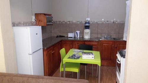 a small kitchen with a green table and a white refrigerator at Tehilah in Sabie