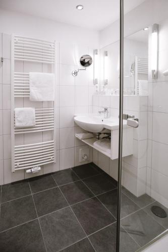 a white bathroom with a sink and a shower at Hotel Stadt Kassel in Rinteln
