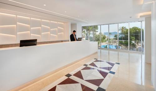 a man in a suit standing at a counter in a lobby at Hipotels Bahia Cala Millor - Adults Only in Cala Millor