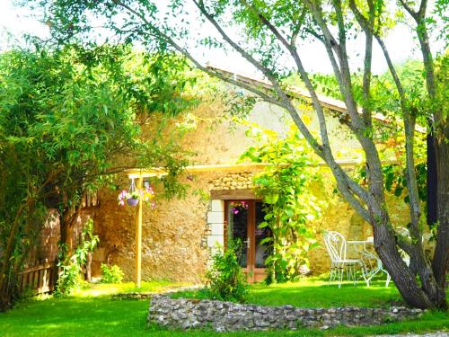 a stone house with a table and chairs in a yard at La Belle Verte in Grignols Dordogne