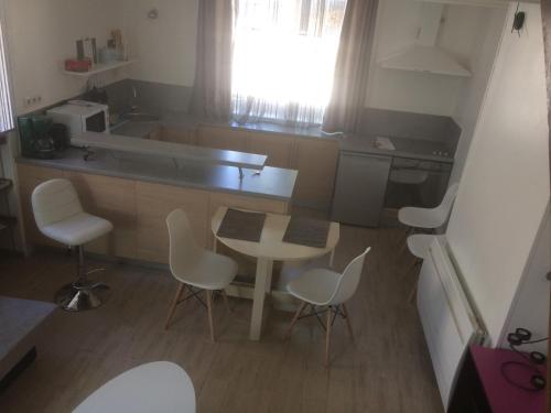 eine kleine Küche mit einem Tisch und weißen Stühlen in der Unterkunft Guitte family in Poilly-sur-Serein