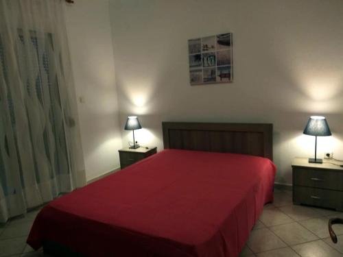 ネア・スキオニにあるRoses RT apartments Skioni Iのベッドルーム1室(赤いベッド1台、ランプ付きのナイトスタンド付)