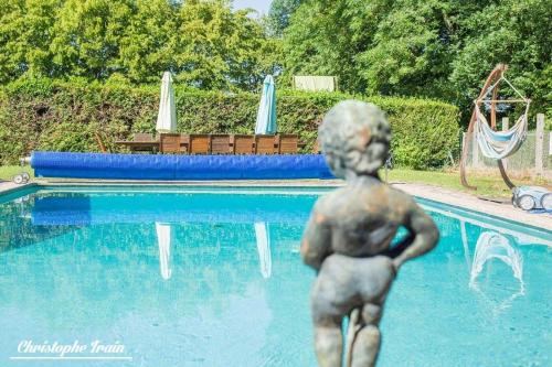 a statue of a boy standing in front of a swimming pool at Manoir de la Perrière maison d'hôtes in Messas