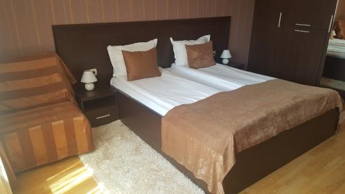 a bedroom with a large bed and a chair at Hotel Alegra in Velingrad