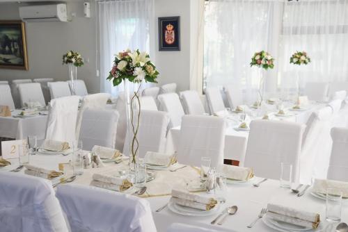 a room filled with white tables with white chairs and flowers at Hotel MK, Plavi restoran, Loznica in Loznica