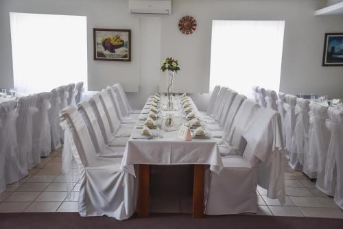a long table in a room with white chairs at Hotel MK, Plavi restoran, Loznica in Loznica