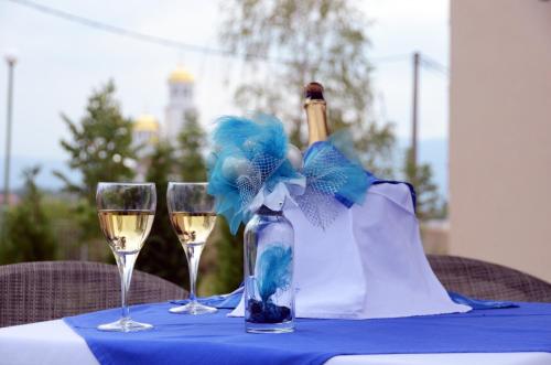 a table with a bottle of wine and two glasses at Hotel MK, Plavi restoran, Loznica in Loznica