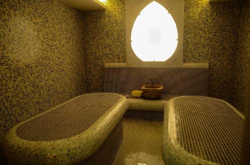 a bathroom with two beds and a window and a tub at Hotel Alegra in Velingrad