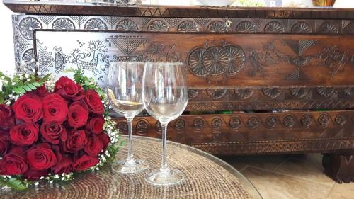 a table with two wine glasses and a bouquet of roses at Hotel Sa Suergia in Villasimius