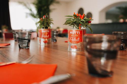 a wooden table with red cans with flowers in them at Botango in Parcines