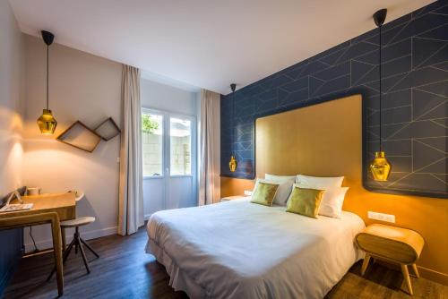 a hotel room with a bed and a desk at The Originals Boutique, Hôtel Le Londres, Saumur in Saumur