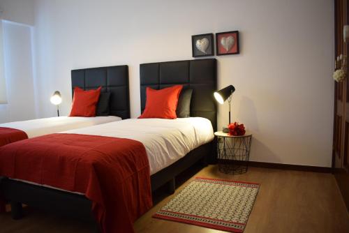um quarto com 2 camas e almofadas vermelhas em Casa Lisboa Oriente em Lisboa