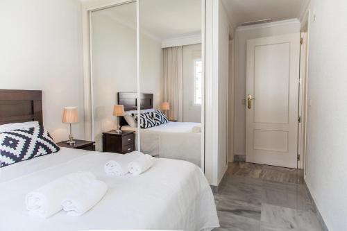 マルベーリャにあるDama de Noche RDR105の白いベッドルーム(ベッド1台、鏡付)