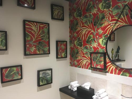 a bathroom with a mirror and paintings on the wall at The Originals Boutique, Hôtel Le Londres, Saumur in Saumur