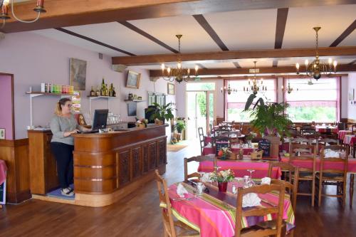 サン・ジャン・ル・トマにあるHotel Des Bainsのレストランのカウンターに立つ女