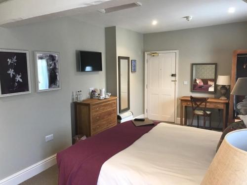 a bedroom with a large bed and a desk at The George Inn - Lacock in Lacock