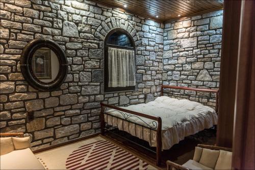 a stone walled bedroom with a bed and a mirror at Stone Mansion Anavryti, ΑΜΑ 20569 in Mystras