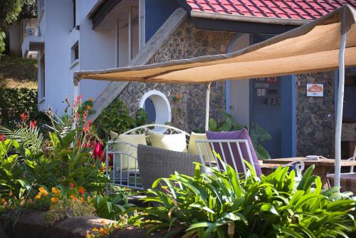 a patio with chairs and an umbrella in a garden at Boulevard Inn Mt Meru in Arusha