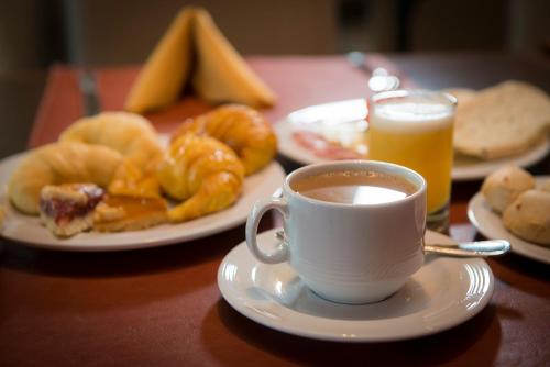 einen Tisch mit einer Tasse Kaffee und Teller mit Speisen in der Unterkunft Grand Crucero Hotel in Puerto Iguazú