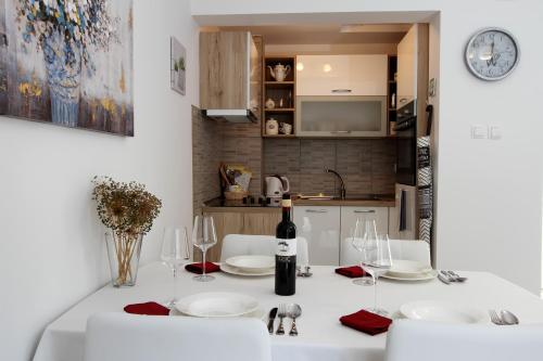 a dining room with a white table with a bottle of wine at Apartman Ana in Otočac