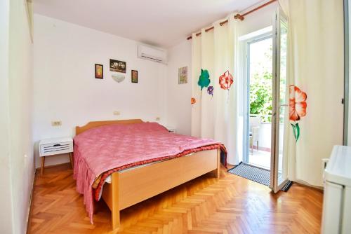 ein Schlafzimmer mit einem Bett mit einer rosa Decke in der Unterkunft Apartments Villa Milenka in Novalja