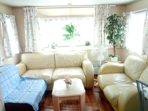 a living room with a white couch and two chairs at Ubytovani v mobilnim domku in Sobotka