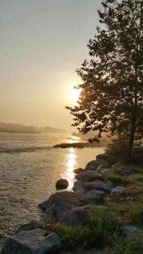 a sunset over a body of water with a tree and rocks at Playa Di Valverde in Galliate