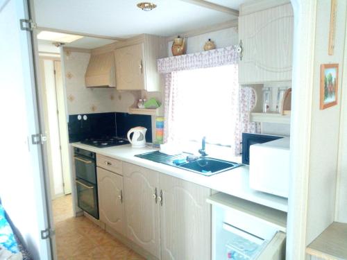 a kitchen with white cabinets and a sink and a window at Ubytovani v mobilnim domku in Sobotka