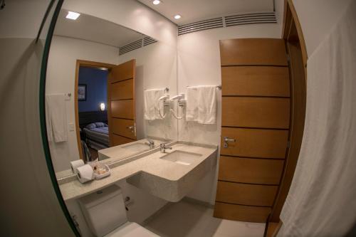 een badkamer met een wastafel en een spiegel bij Eston Hotel - LOCALIZAÇÃO CENTRAL PRIVILEGIADA -PET FRIENDLY in Chapecó