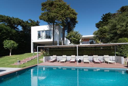a swimming pool with chairs and a house at Cascais Casa Laranja Boutique House in Cascais