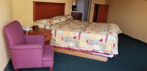 a hotel room with a bed and a desk and a phone at Wolds Motel - Mt. Pleasant in Mount Pleasant