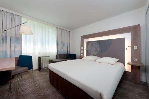 A bed or beds in a room at Novotel Fontainebleau Ury