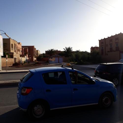 a blue car is parked on a street at Oasispalmares in Er Rachidia