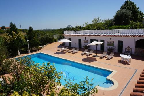 a swimming pool with chairs and a building at Quinta das Camélias in Tremês