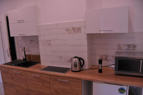 a kitchen with white cabinets and a tea kettle on a counter at Apartamenty Centrum Słupsk in Słupsk