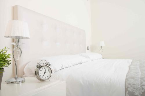 a bed with white sheets and an alarm clock on a table at Cancun Blue Airport in Cancún