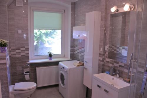 a bathroom with a toilet a sink and a washing machine at Apartamenty Centrum Słupsk in Słupsk