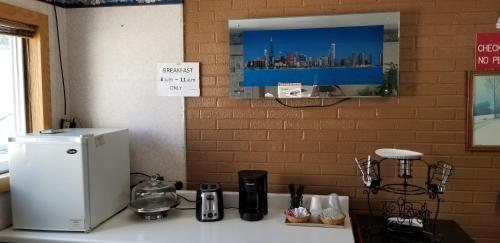 a kitchen counter with a refrigerator and a sign on the wall at Wolds Motel - Mt. Pleasant in Mount Pleasant