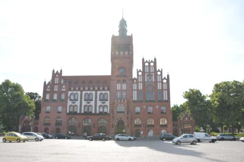 a large brick building with cars parked in a parking lot at Apartamenty Centrum Słupsk in Słupsk