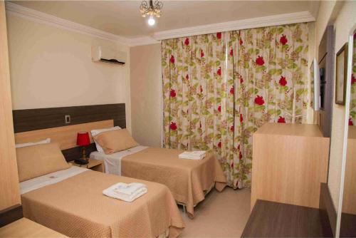 a room with two beds and a curtain with flowers at Royal Plaza Hotel in Apucarana