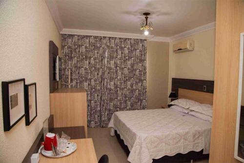 a bedroom with a bed and a table and a window at Royal Plaza Hotel in Apucarana