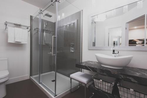 a bathroom with a glass shower and a sink at Les suites de la chocolaterie in Ville-Marie